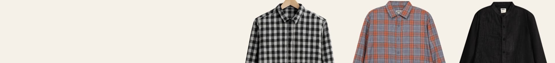 Three shirts on hangers with a plain background