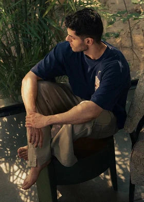A man wearing navy blue t-shirt and brown pant sitting on a chair