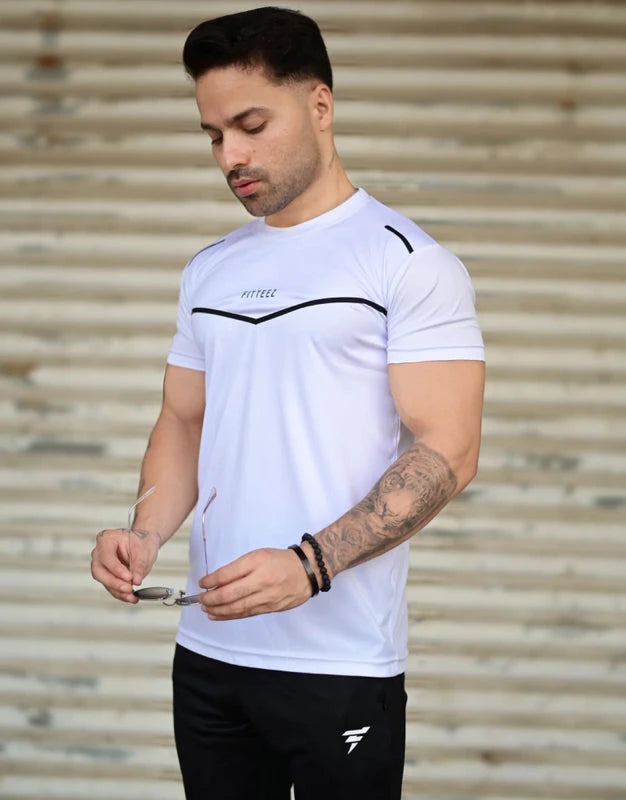 Man wearing a white athletic shirt with black accents and black shorts, standing against a metallic background. Leisure Icon White & Black Track Suit Royal Outfits Track Suits