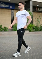 Man wearing a white t-shirt and black pants walking outdoors. Leisure Icon White & Black Track Suit Royal Outfits Track Suits - Leisure Icon White & Black Track Suit - Royal Outfits - Track Suits