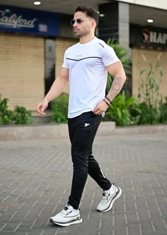 Man wearing a white t-shirt and black pants walking outdoors. Leisure Icon White & Black Track Suit Royal Outfits Track Suits - Leisure Icon White & Black Track Suit - Royal Outfits - Track Suits