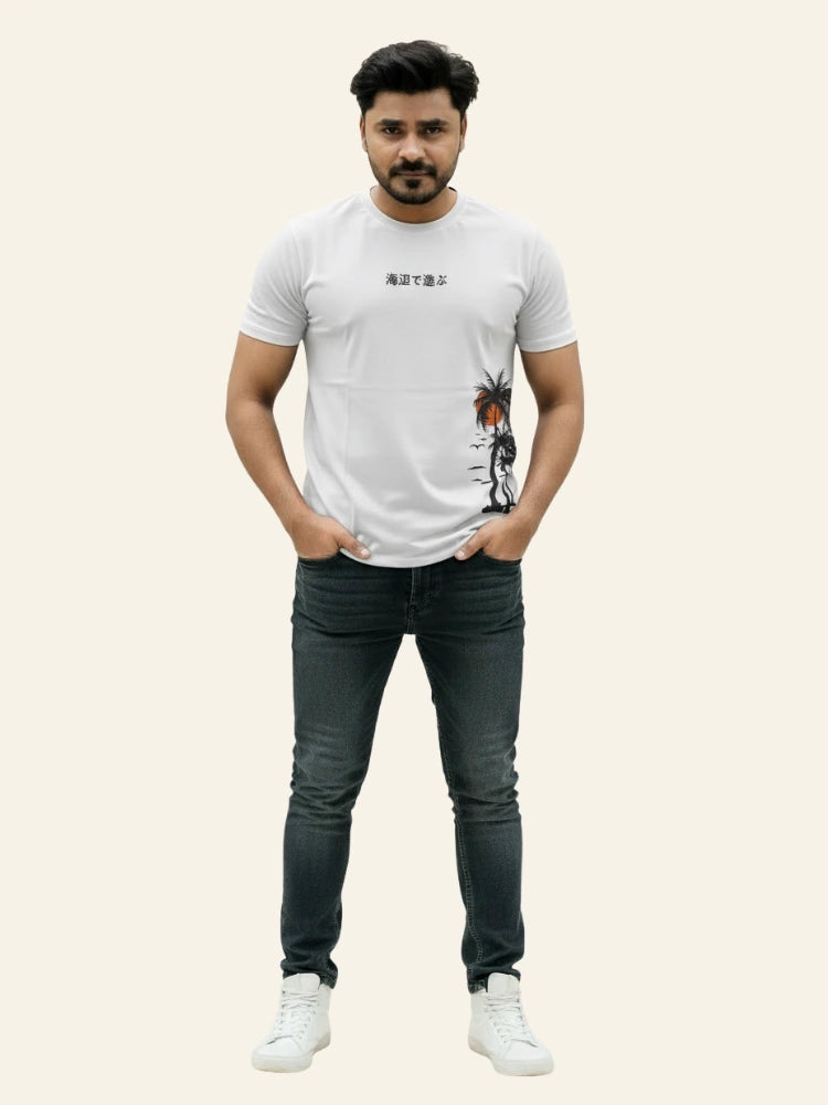 Man wearing a white t-shirt with graphics and text, black jeans, and white sneakers on a beige background Graphic White Palm T-Shirt Royal Outfits Graphic T Shirts