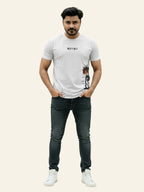Man wearing a white t-shirt with graphics and text, black jeans, and white sneakers on a beige background Graphic White Palm T-Shirt Royal Outfits Graphic T Shirts