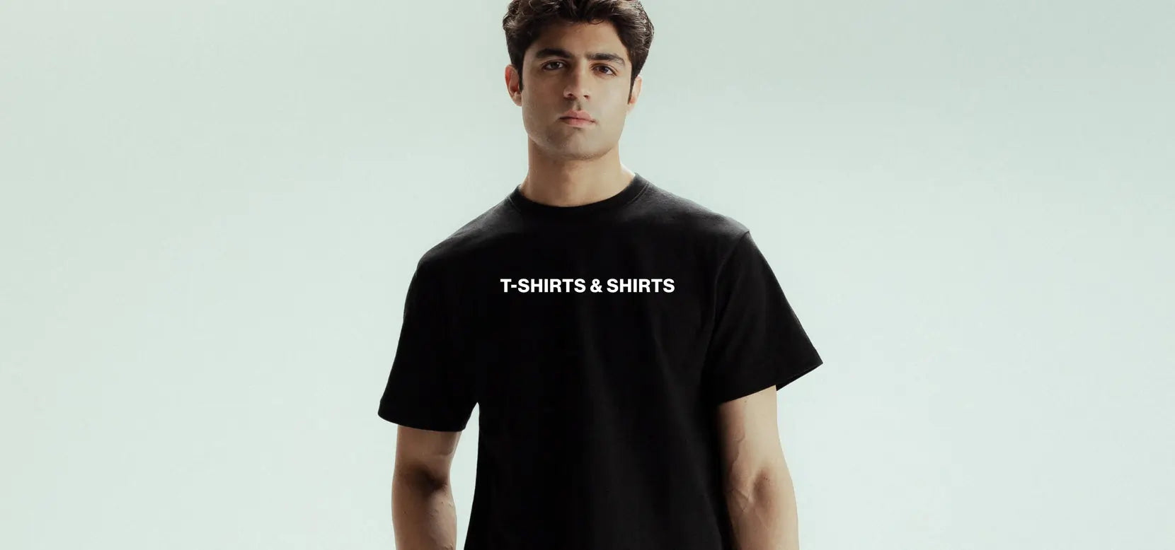 Person wearing a black t-shirt with 'T-SHIRTS & SHIRTS' text on a light gray background