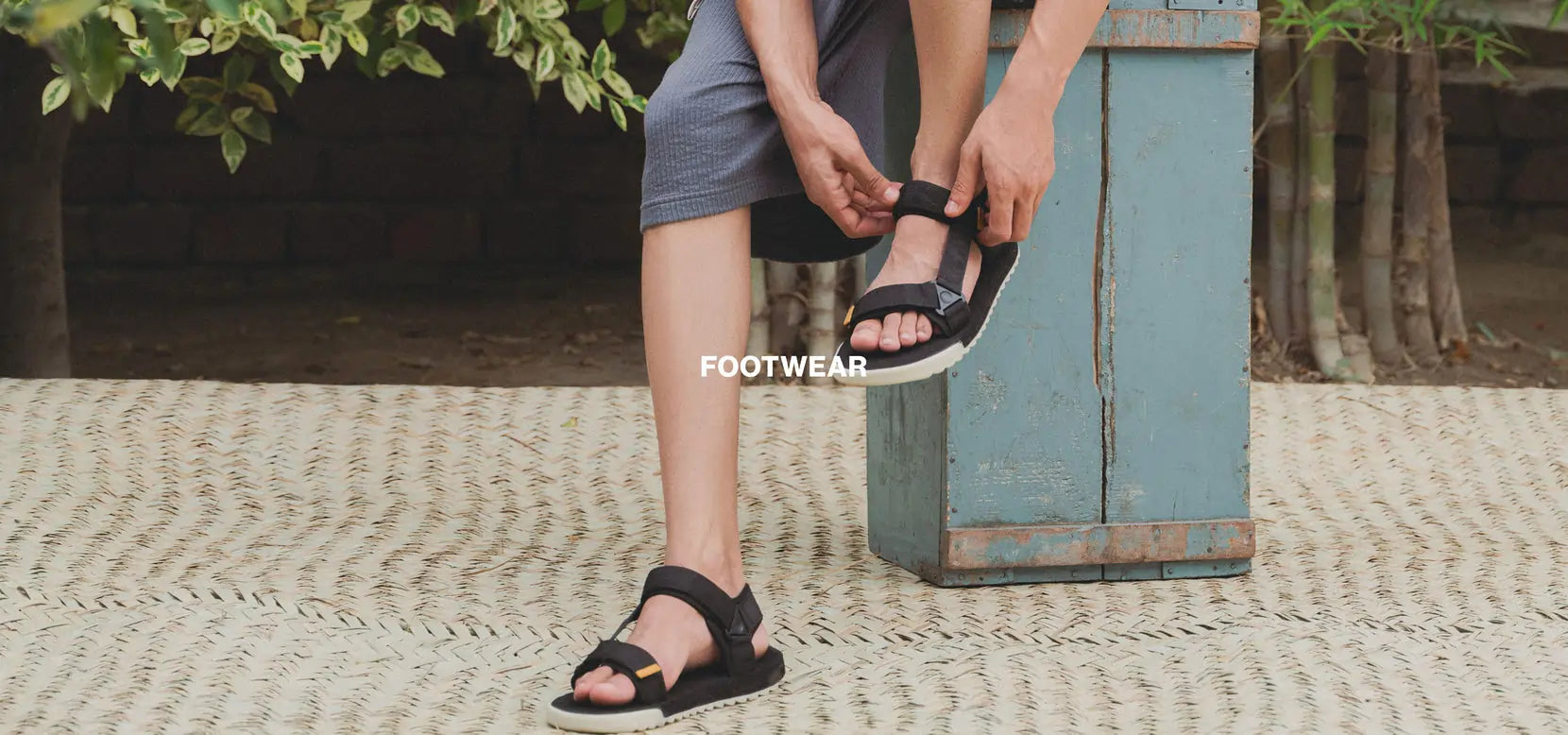 Person wearing black sandals on a textured surface with 'FOOTWEAR' text overlay.