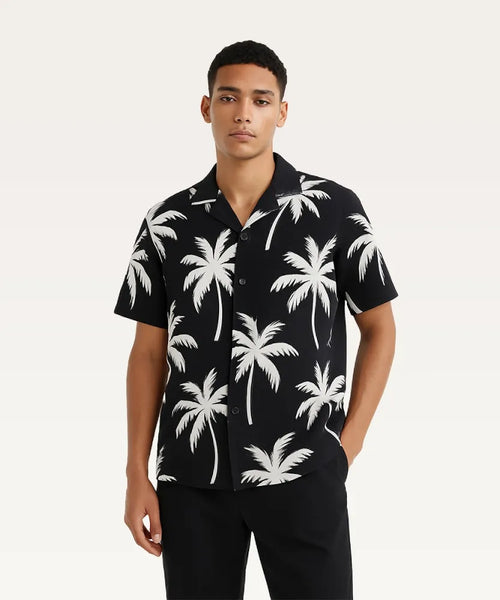 Man wearing a black shirt with white palm tree pattern on a plain background Black Shirt with Golden Palm Print Royal Outfits Printed Shirts