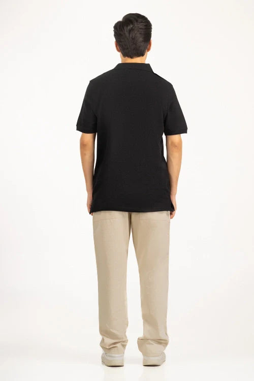 Person wearing a black polo shirt and beige pants on a white background Black Regular Fit Men POLO T-Shirt Royal Outfits POLO T Shirts