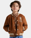 Child wearing a brown varsity jacket with a logo on a white background