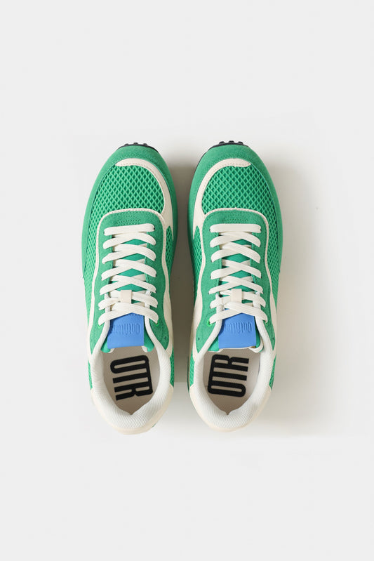 Green sneakers with white laces on a light gray background