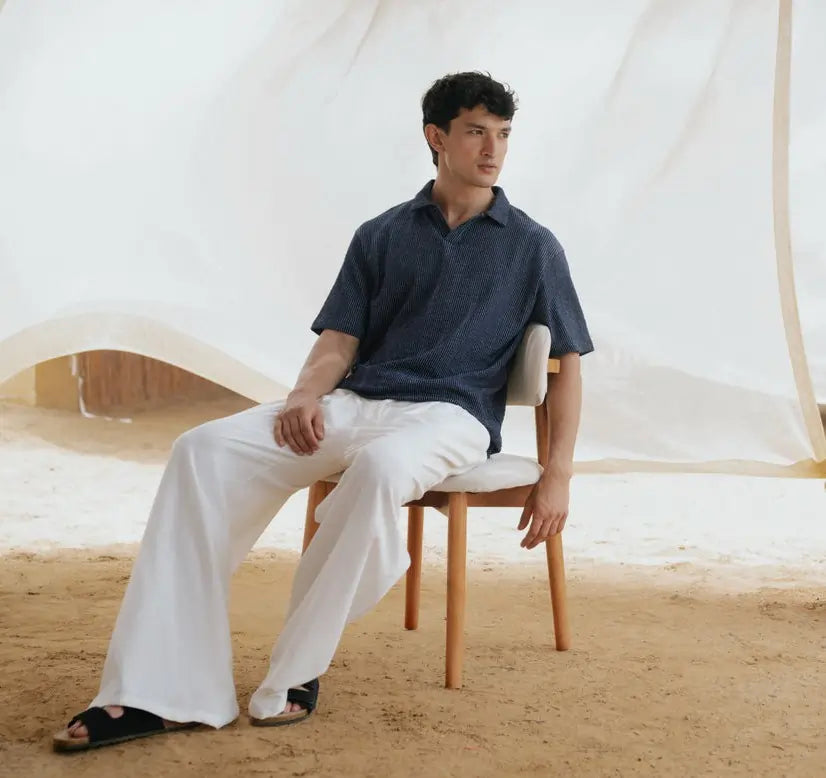 Man sitting on a chair in a desert-like setting with a tent in the background