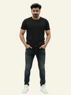 Man wearing a black t-shirt, dark jeans, and white sneakers on a plain background Plain Colourful T-Shirt Royal Outfits Plain T-Shirts