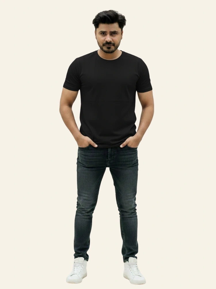 Man wearing a black t-shirt, dark jeans, and white sneakers on a plain background Plain Colourful T-Shirt Royal Outfits Plain T-Shirts