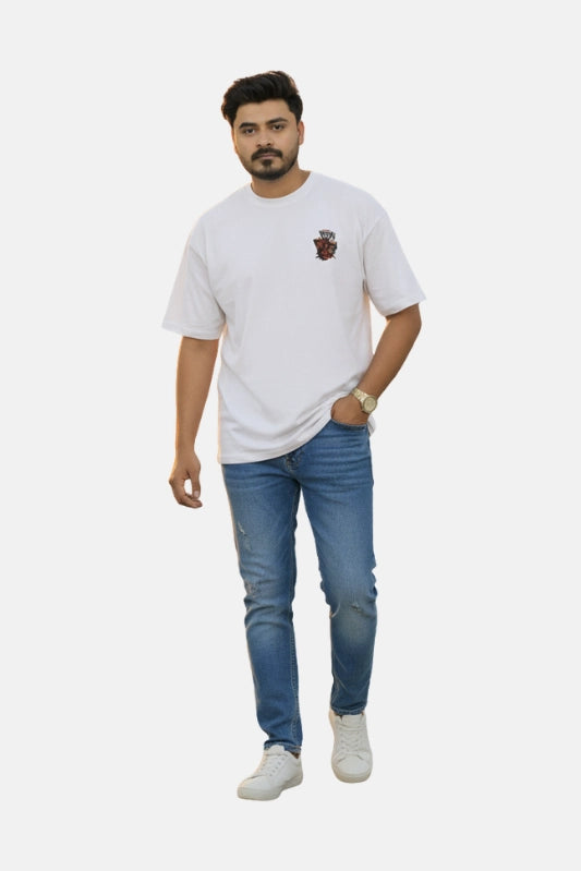 Man wearing a white t-shirt with a logo and blue jeans on a light gray background Graphic White Drop Shoulder "Dhool" T-Shirt Royal Outfits Drop Shoulder T-Shirts - Graphic White Drop Shoulder "Dhool" T-Shirt - Royal Outfits - Drop Shoulder T-Shirts