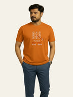 Man wearing an orange t-shirt with text and design on a plain background Graphic Orange Crossword T-Shirt Royal Outfits Graphic T Shirts