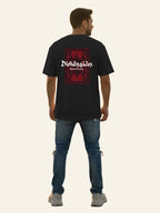 Man wearing a black t-shirt with a red and white graphic design on the back, standing against a plain background. Graphic Black Drop Shoulder Dimension T-Shirt Royal Outfits Drop Shoulder T-Shirts
