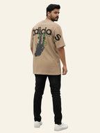 Man wearing a beige Adidas t-shirt with a graphic design on a white background