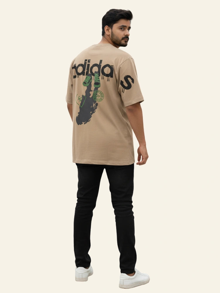 Man wearing a beige Adidas t-shirt with a graphic design on a white background