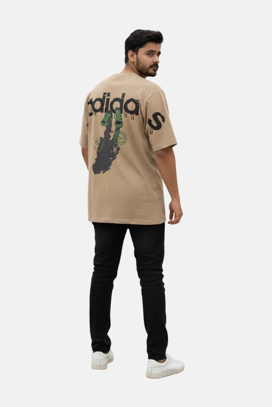 Man wearing a beige Adidas t-shirt with a graphic design on a white background - Graphic Beige Drop Shoulder T-Shirt with Adidas Logo - Royal Outfits - Drop Shoulder T-Shirts - Graphic Beige Drop Shoulder T-Shirt with Adidas Logo - Royal Outfits