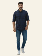 Man wearing a navy blue shirt and jeans on a plain background
