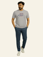 Man wearing a gray t-shirt with a logo and dark blue pants on a white background Light Grey T Hedges T-Shirt Royal Outfits Printed T Shirts