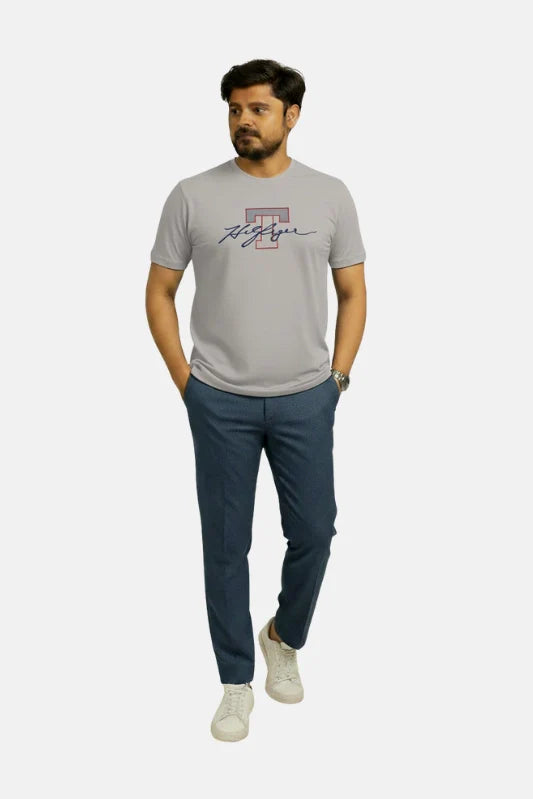 Man wearing a gray t-shirt with a logo and dark blue pants on a white background Light Grey T Hedges T-Shirt Royal Outfits Printed T Shirts - Light Grey T Hedges T-Shirt - Royal Outfits - Printed T Shirts - Light Grey T Hedges T-Shirt - Royal Outfits