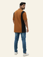 Man wearing a brown and black polo shirt with blue jeans on a beige background