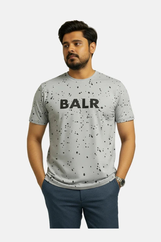 Man wearing a gray t-shirt with 'BALR.' logo on a beige background Light Grey ‘BALR’ T-Shirt Royal Outfits Graphic T Shirts - Light Grey ‘BALR’ T-Shirt - Royal Outfits - Graphic T Shirts - Light Grey ‘BALR’ T-Shirt - Royal Outfits