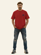 Man wearing a red t-shirt and blue jeans on a plain background Graphic Red Drop Shoulder Spider T-Shirt Royal Outfits Drop Shoulder T-Shirts
