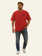 Man wearing a red t-shirt and blue jeans on a plain background Graphic Red Drop Shoulder Spider T-Shirt Royal Outfits Drop Shoulder T-Shirts