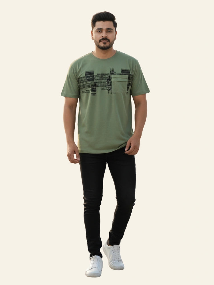 Man wearing a green t-shirt with black text pattern and black pants on a white background
