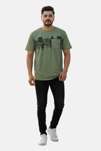 Man wearing a green t-shirt with black text pattern and black pants on a white background - Graphic Light Green Print T-Shirt with Chest Pocket - Royal Outfits - Printed T Shirts - Graphic Light Green Print T-Shirt with Chest Pocket - Royal Outfits