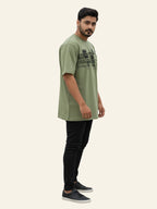Man wearing a green t-shirt and black pants on a white background