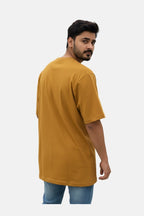 Man wearing a mustard t-shirt on a plain background - Graphic Mustard Colour T-Shirt with Chest Pocket - Royal Outfits - Printed T Shirts - Graphic Mustard Colour T-Shirt with Chest Pocket - Royal Outfits
