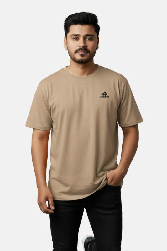 Man wearing a beige Adidas t-shirt on a plain background - Graphic Beige Drop Shoulder T-Shirt with Adidas Logo - Royal Outfits - Drop Shoulder T-Shirts - Graphic Beige Drop Shoulder T-Shirt with Adidas Logo - Royal Outfits