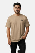 Man wearing a beige Adidas t-shirt on a plain background - Graphic Beige Drop Shoulder T-Shirt with Adidas Logo - Royal Outfits - Drop Shoulder T-Shirts - Graphic Beige Drop Shoulder T-Shirt with Adidas Logo - Royal Outfits