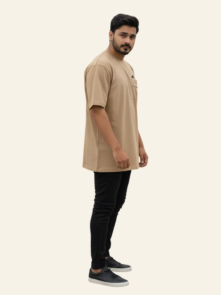 Man wearing a beige long-sleeve shirt and black pants on a white background