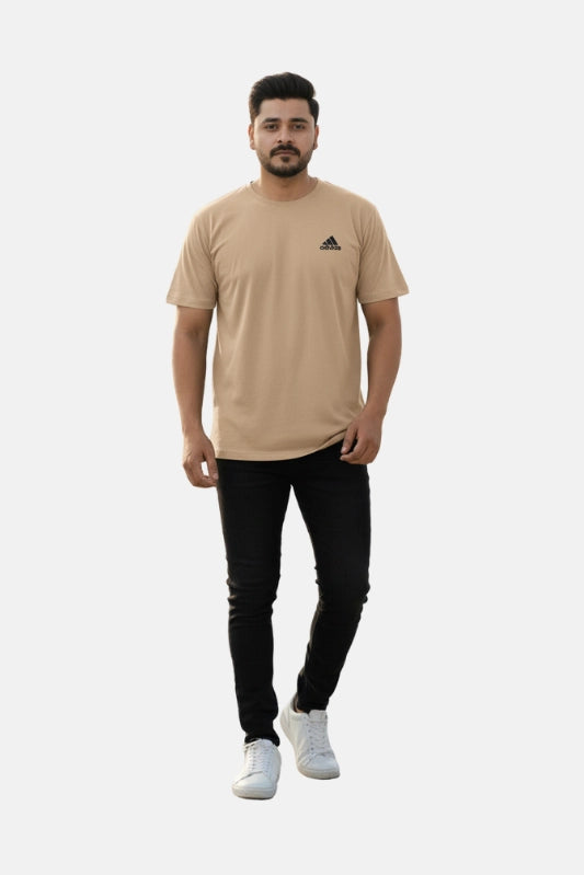 Man wearing a beige Adidas t-shirt and black pants on a white background - Graphic Beige Drop Shoulder T-Shirt with Adidas Logo - Royal Outfits - Drop Shoulder T-Shirts - Graphic Beige Drop Shoulder T-Shirt with Adidas Logo - Royal Outfits