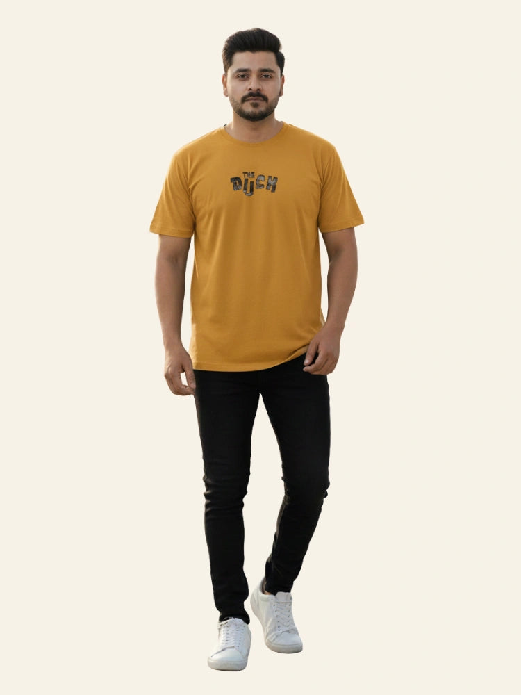 Man wearing a mustard yellow t-shirt with a logo on a white background