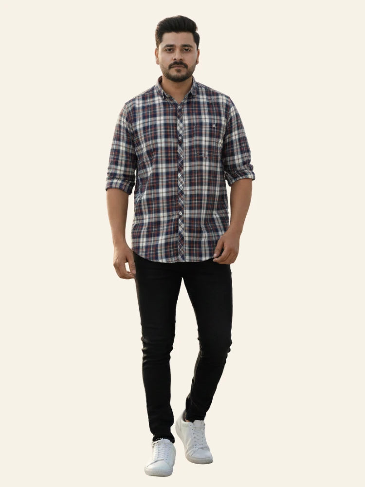 Man wearing a checkered shirt, black pants, and white sneakers on a plain background