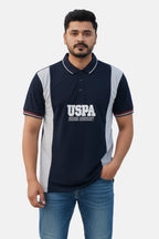 Man wearing a navy blue polo shirt with 'USPA' branding on a beige background - Men’s Black USPA Contrast Panel Polo T-Shirt - Royal Outfits - POLO T Shirts - Men’s Black USPA Contrast Panel Polo T-Shirt - Royal Outfits