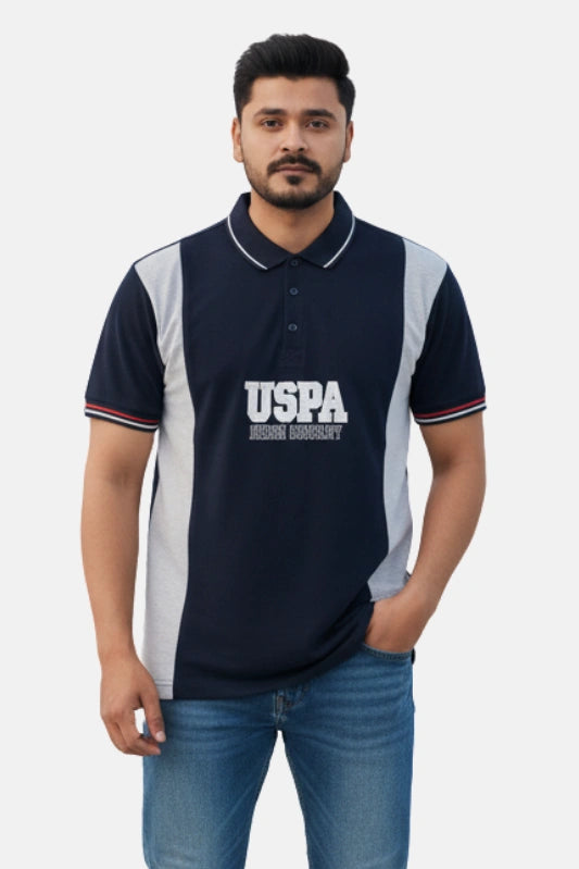 Man wearing a navy blue polo shirt with 'USPA' branding on a beige background - Men’s Black USPA Contrast Panel Polo T-Shirt - Royal Outfits - POLO T Shirts - Men’s Black USPA Contrast Panel Polo T-Shirt - Royal Outfits