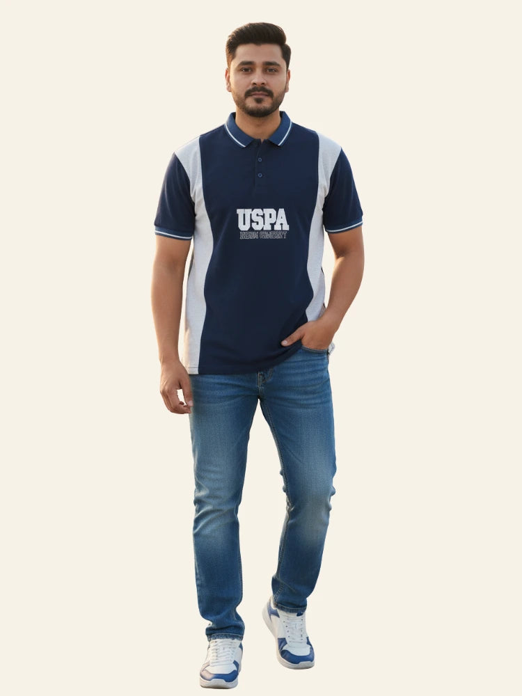 Man wearing a navy blue polo shirt with 'USPA' logo and blue jeans on a white background