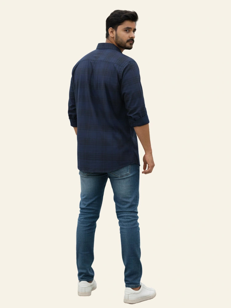 Man wearing a navy blue shirt and jeans on a beige background