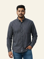 Man wearing a gray checkered shirt and blue jeans on a beige background