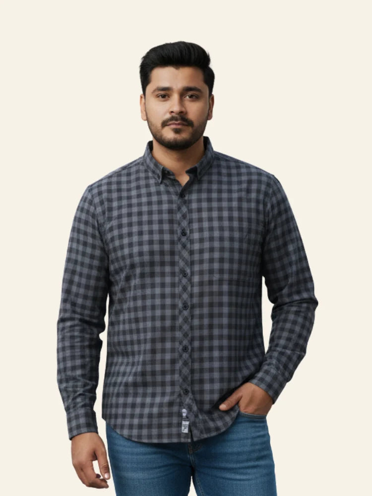 Man wearing a gray checkered shirt and blue jeans on a beige background