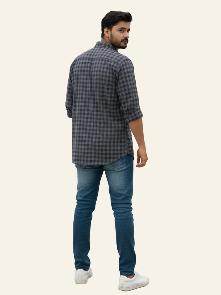 Man wearing a checkered shirt and jeans on a plain background