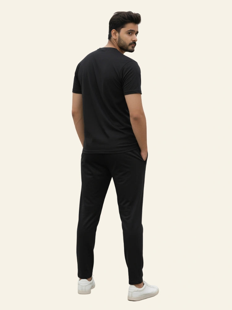Man wearing a black t-shirt and black pants on a beige background