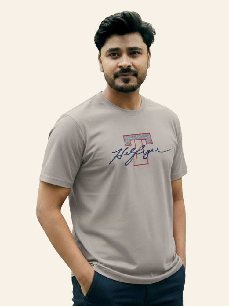 Man wearing a gray t-shirt with a logo on a plain background Light Grey T Hedges T-Shirt Royal Outfits Printed T Shirts