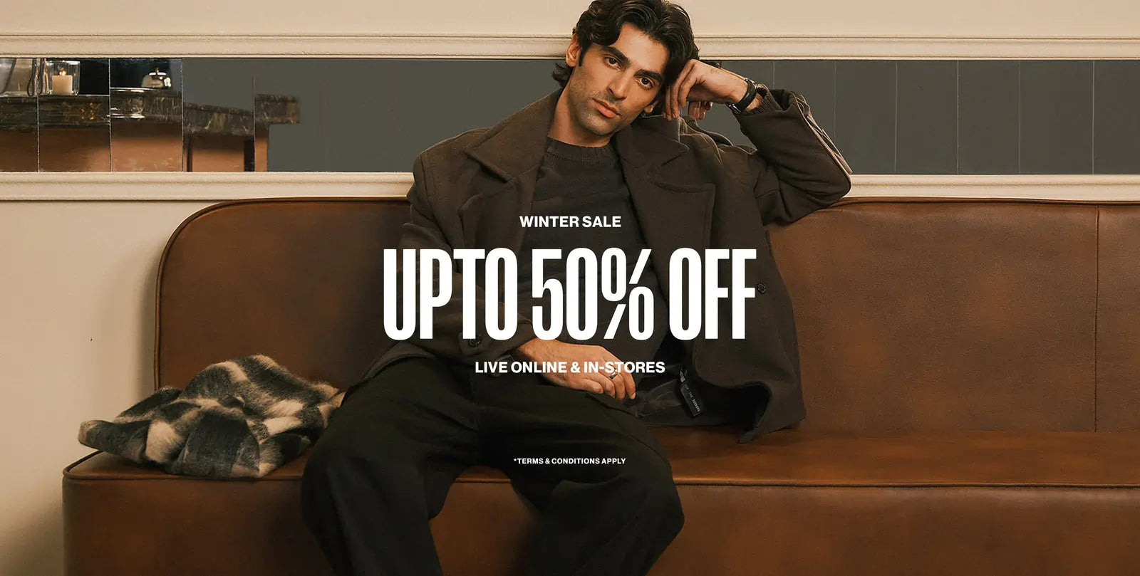 Man sitting on a brown couch with promotional text for a winter sale.